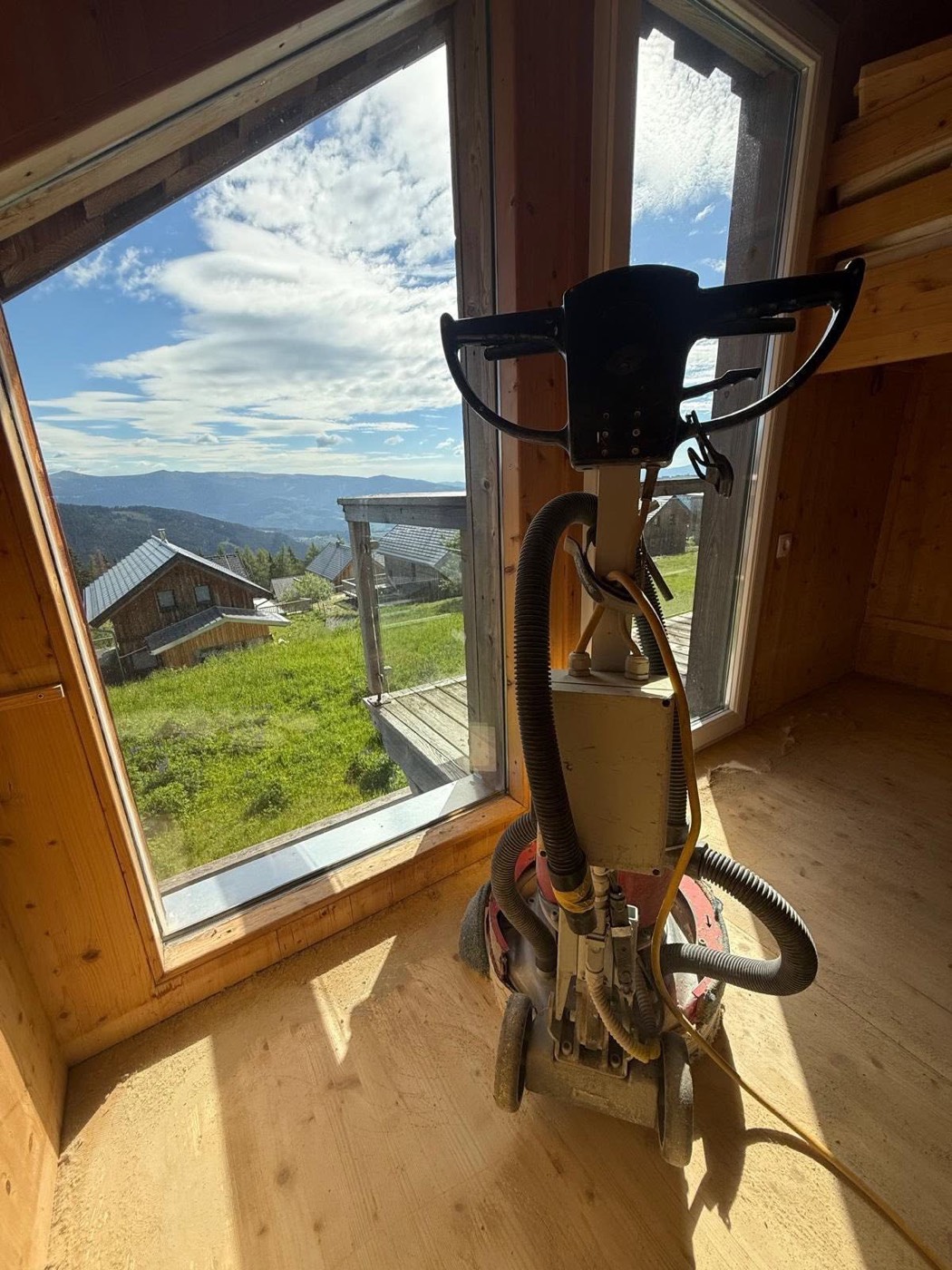 Parkettschleifmaschine in einer Holzhütte mit Bergblick